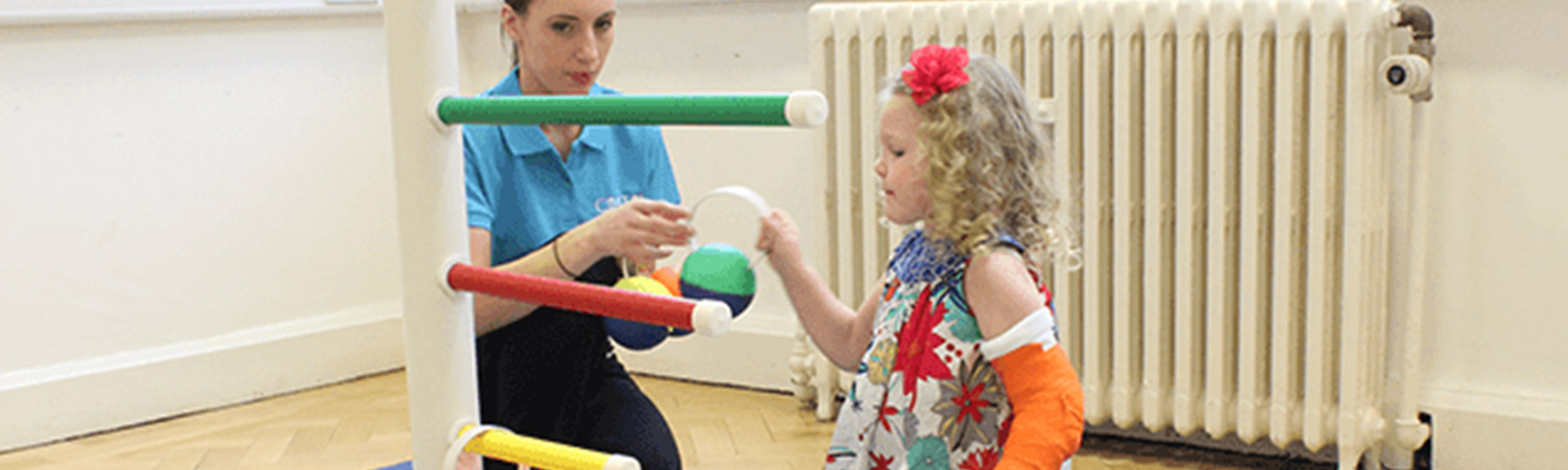 CIMT child putting hoops on a pole with their personal physiotherapist  