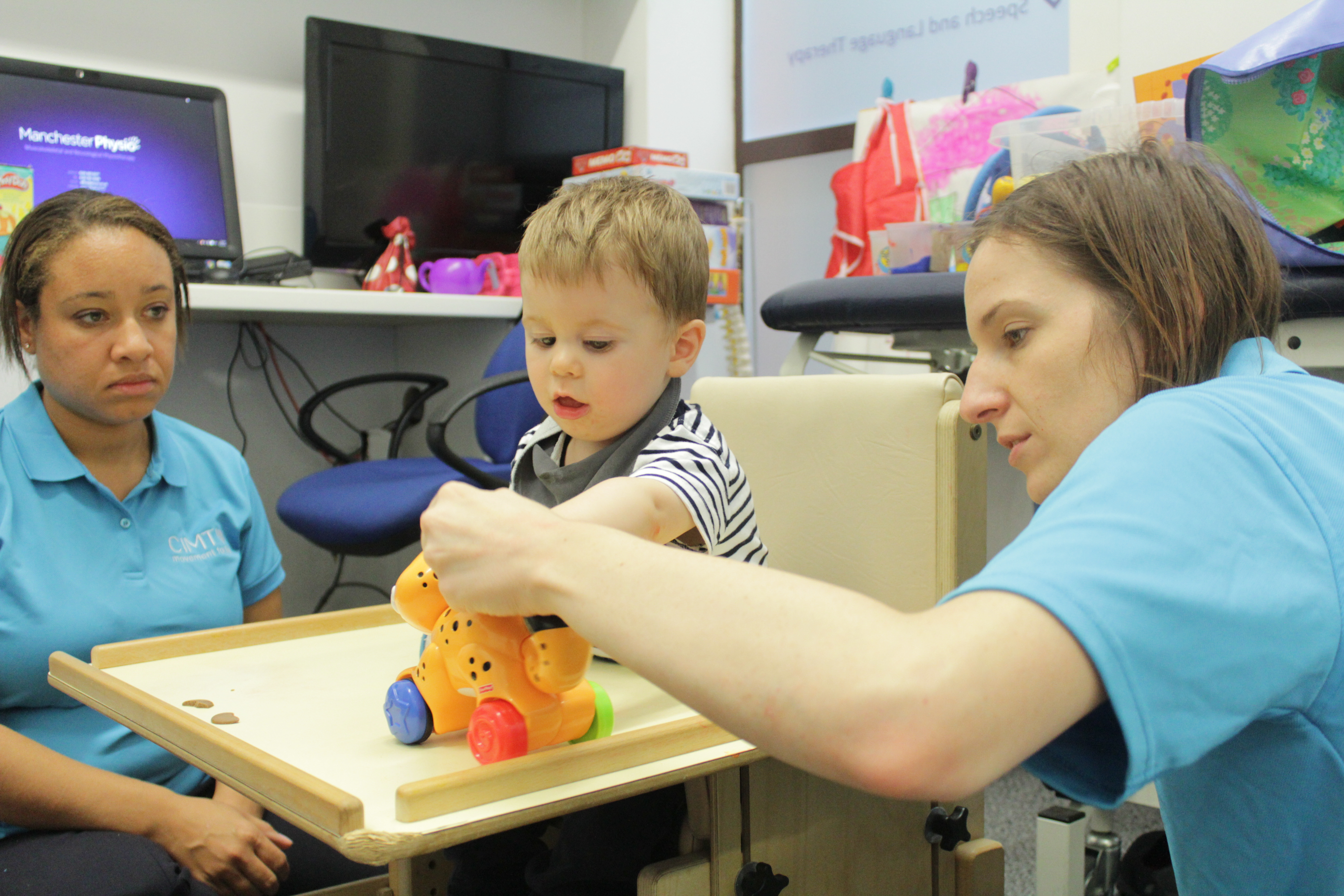 Thomas playing with a toy with CIMT therapists